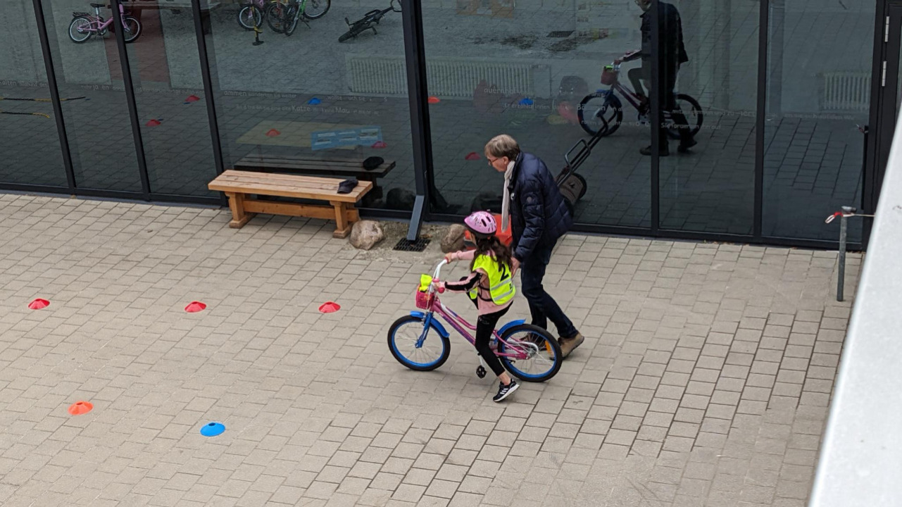 Mädchen bekommt Hilfestellung beim Fahrradfahren