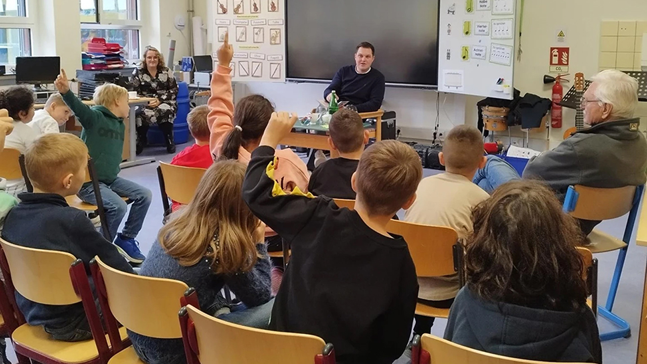 Schüler im Klassenzimmer lauschen dem vorlesenden Landtagsabgeordneten Philipp Raulfs